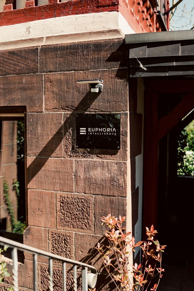 Eingang zum EUPHORIA Hauptstandort Marburg mit Firmenschild an der Sandsteinfassade