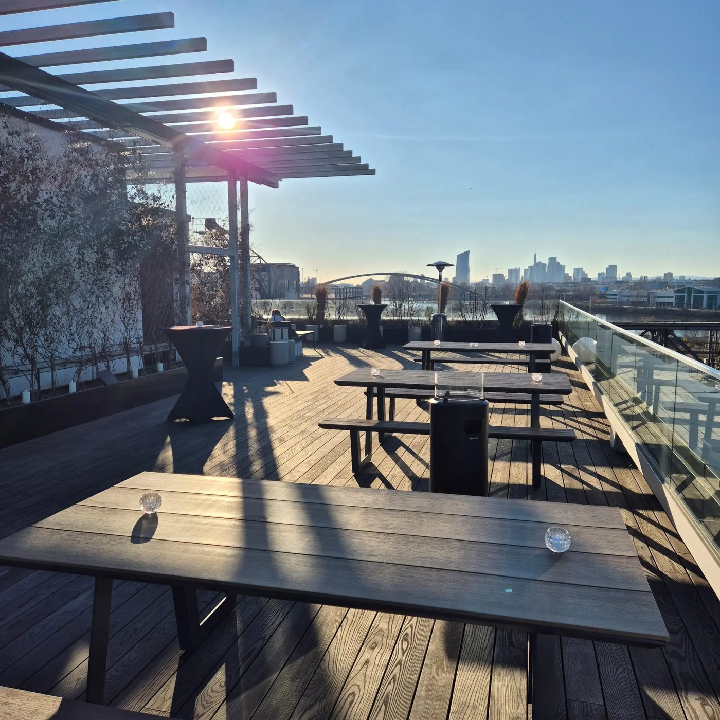 Dachterrasse am Standort Offenbach am Main mit Holztischen und Blick auf die Skyline von Frankfurt